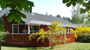 A house with a red exterior, a covered porch, and a view of a person outside. - Unique Seaside Holiday Home in Hadsund near Terrace (Hadsund)