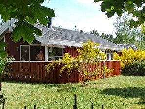Ett hus med en röd fasad, en inglasad veranda och utsikt över en person som befinner sig utomhus.