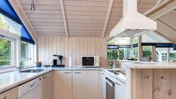 Una cocina moderna con paneles de madera, lavavajillas integrado y un amplio ventanal con vistas al exterior.