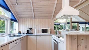 Una cocina moderna con paneles de madera, lavavajillas empotrado y un ventanal grande que proporciona luz natural.