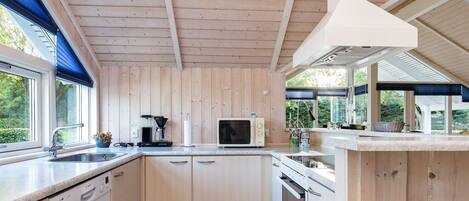 A modern kitchen with wooden paneling, a built-in dishwasher, and a large window providing natural light.