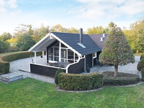 A modern house with a sloped roof, large windows, and a chimney.