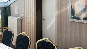 A room with a wooden exterior, a door leading to a dark interior, a radiator, and a framed picture on the wall. - Holiday Home in Otterndorf (Otterndorf)