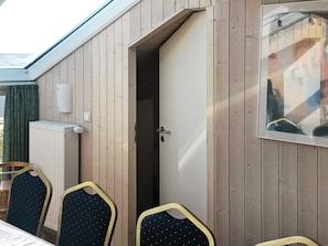 A room with a wooden exterior, a door leading to a dark interior, a radiator, and a framed picture on the wall. - Holiday Home in Otterndorf (Otterndorf)