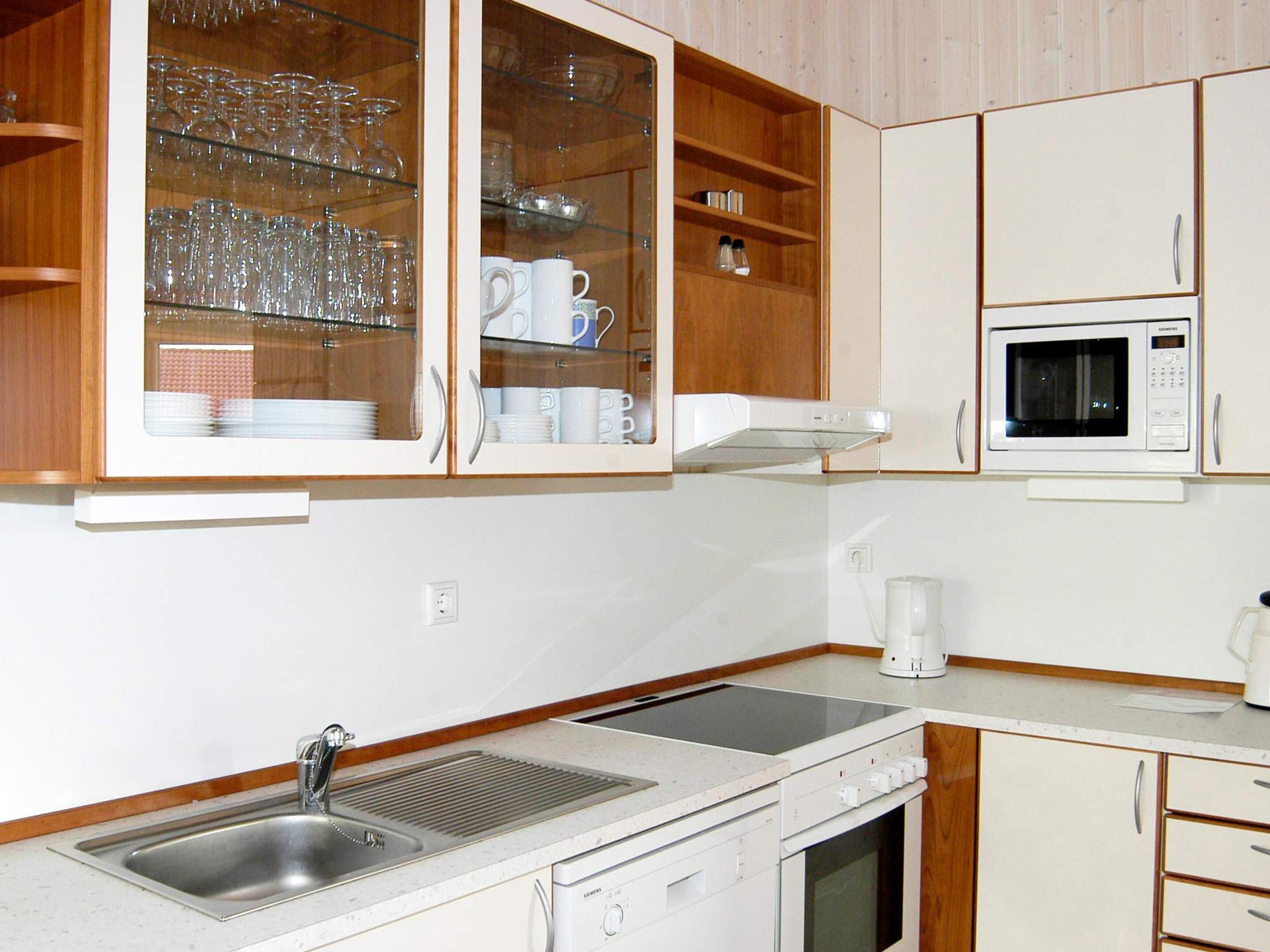 A kitchen with a built-in microwave, a coffee maker, and a sink with a stainless steel basin.