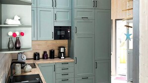 A modern kitchen with grey cabinets, a wooden countertop, and a built-in microwave. - Holiday Home in Otterndorf (Otterndorf)