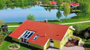 A yellow house with a red roof, a small deck, and a pond in the background. - Holiday Home in Otterndorf (Otterndorf)