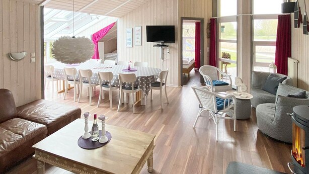 A spacious living area with a wooden coffee table, leather sofas, and a fireplace. - Holiday Home in Otterndorf (Otterndorf)