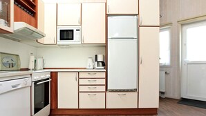 A compact kitchen with a microwave, stove, and refrigerator. - Holiday Home in Otterndorf (Otterndorf)