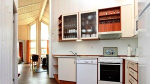 A compact kitchen with wooden cabinets, a dishwasher, an oven, and a sink. - Holiday Home in Otterndorf (Otterndorf)