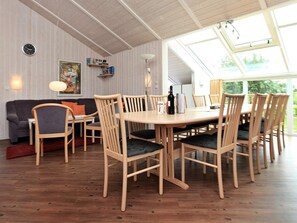 A dining area with a wooden table and chairs, a sofa, and a painting on the wall.