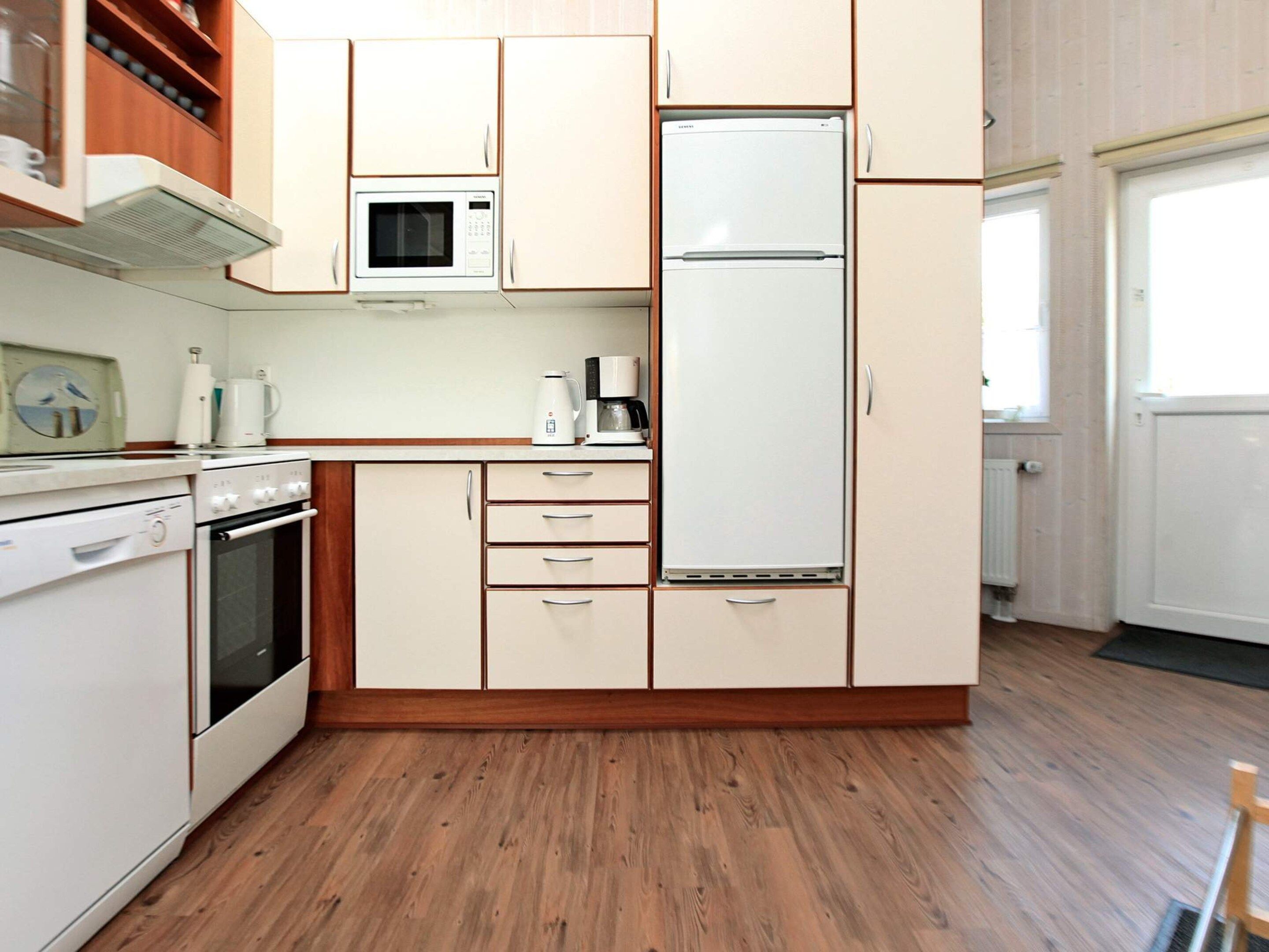 A kitchen with a microwave, stove, refrigerator, and wooden cabinets.