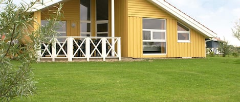 A yellow building with a white porch and a sloped roof.
