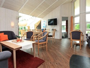 Un vaste espace de vie comprenant une table à manger, des chaises, un canapé et un téléviseur fixé au mur.