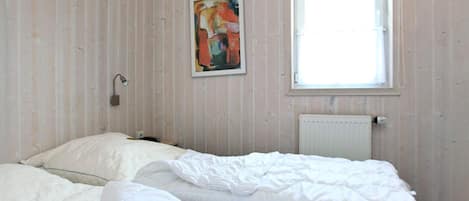 A room with a bed, a painting, a window, and a radiator.