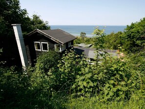 A cabin with a view of the ocean, surrounded by dense greenery. - Lovely Holiday Home in AsnÃ¦s near Sea (Asnaes)