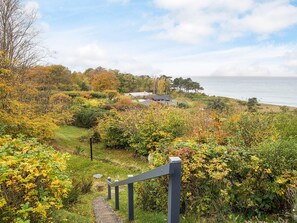 A coastal landscape with a pathway leading to a building with multiple roofs, surrounded by autumn foliage. - Lovely Holiday Home in AsnÃ¦s near Sea (Asnaes)