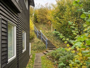 A wooden house with a staircase leading to a garden area. - Lovely Holiday Home in AsnÃ¦s near Sea (Asnaes)