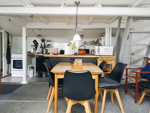 A compact kitchen with a dining area, a white oven, a microwave, and a small sink. - Lovely Holiday Home in AsnÃ¦s near Sea (Asnaes)