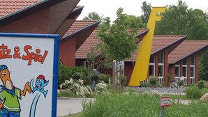 A building with a distinctive yellow structure, a sign with cartoon characters, and a sign indicating a fire hydrant zone. - Holiday Home in Otterndorf (Otterndorf)