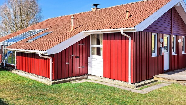 A red building with a sloped roof, solar panels, and a white door. - Holiday Home in Otterndorf (Otterndorf)