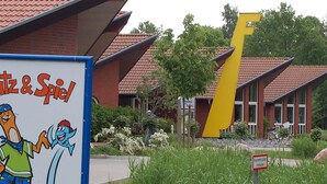 A building with a distinctive yellow structure, a sign with cartoon characters, and a sign indicating a fire hydrant zone. - Holiday Home in Otterndorf (Otterndorf)
