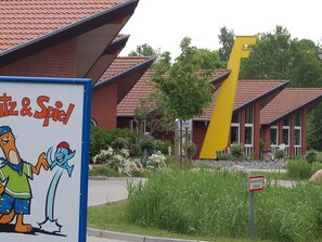 A building with a distinctive yellow structure, a sign with cartoon characters, and a sign indicating a fire hydrant zone. - Holiday Home in Otterndorf (Otterndorf)
