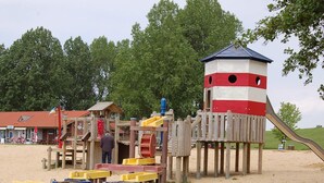 A playground with a slide, climbing structures, and a lookout tower. - Holiday Home in Otterndorf (Otterndorf)