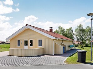 A single-story building with a pitched roof, a small porch, and a visible trash bin.