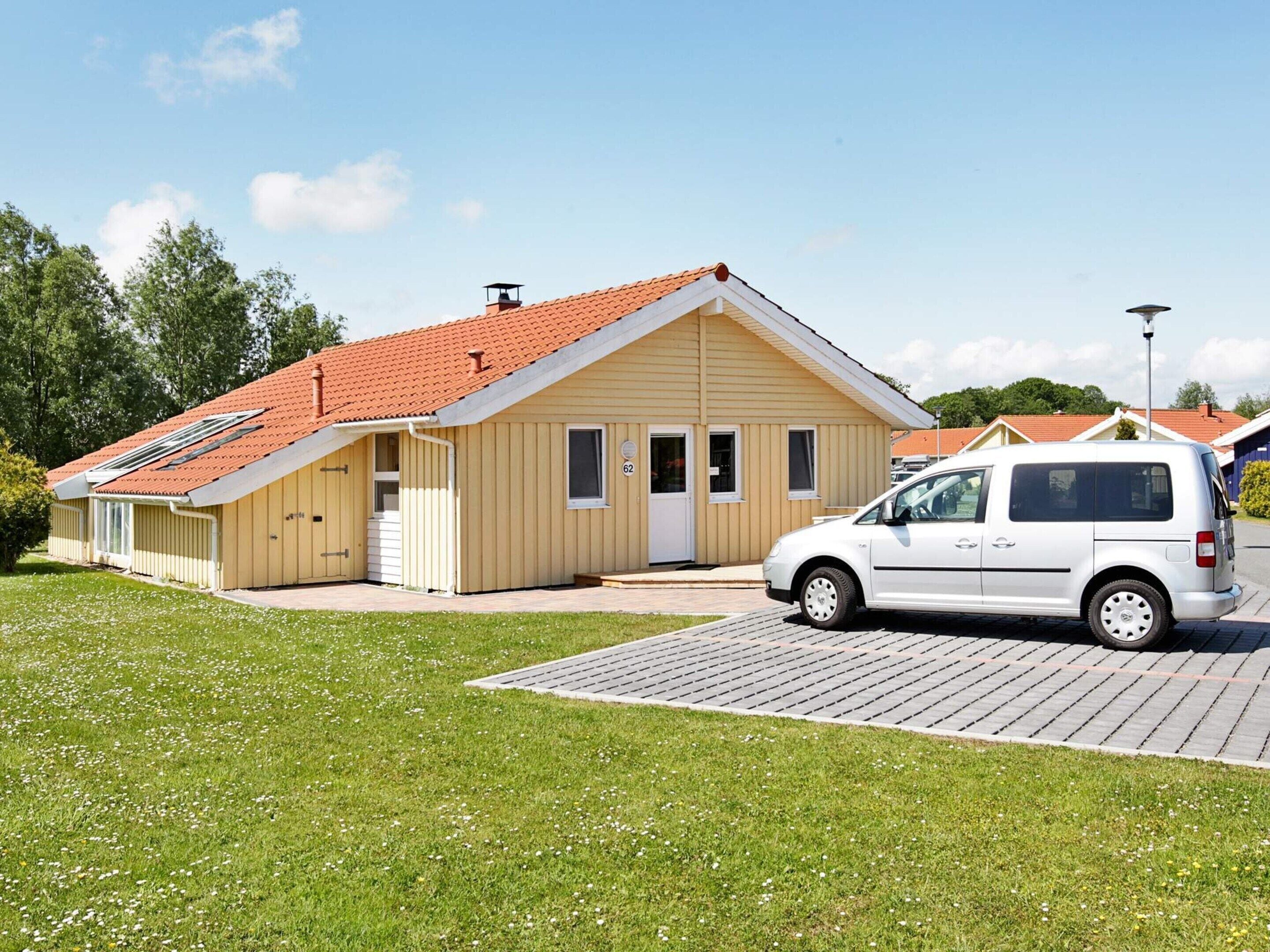 A single-story building with a red-tiled roof, a white van parked in front, and a paved driveway.