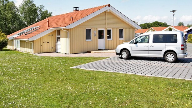 A single-story building with a red-tiled roof, a white van parked in front, and a paved driveway. - Beautiful Holiday Home in LÃ¸gstÃ¸r (Otterndorf)