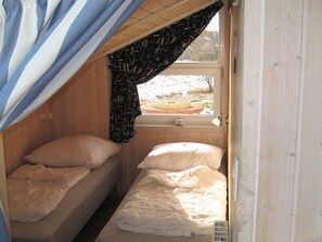 Une petite chambre avec un lit simple, une fenêtre et une porte.