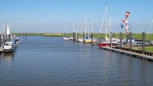 A marina with multiple boats docked, a grassy shoreline, and a clear sky. - Beautiful Holiday Home in LÃ¸gstÃ¸r (Otterndorf)