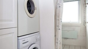 Une buanderie avec des machines à laver superposées, une fenêtre donnant sur un paysage agréable et un radiateur.