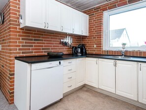 A kitchen with white cabinets, a Bosch dishwasher, and a window with a view of a house. - 8 Person Holiday Home in Harboore (Harboore)