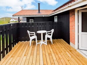 A wooden deck with two white plastic chairs and a small round table.