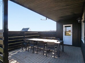 An outdoor patio with a table and chairs, a wooden fence, and a view of the landscape. - 8 Person Holiday Home in Harboore (Harboore)