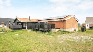 A single-story house with a sloped roof, a fenced backyard, and a small outdoor play area. - 8 Person Holiday Home in Harboore (Harboore)