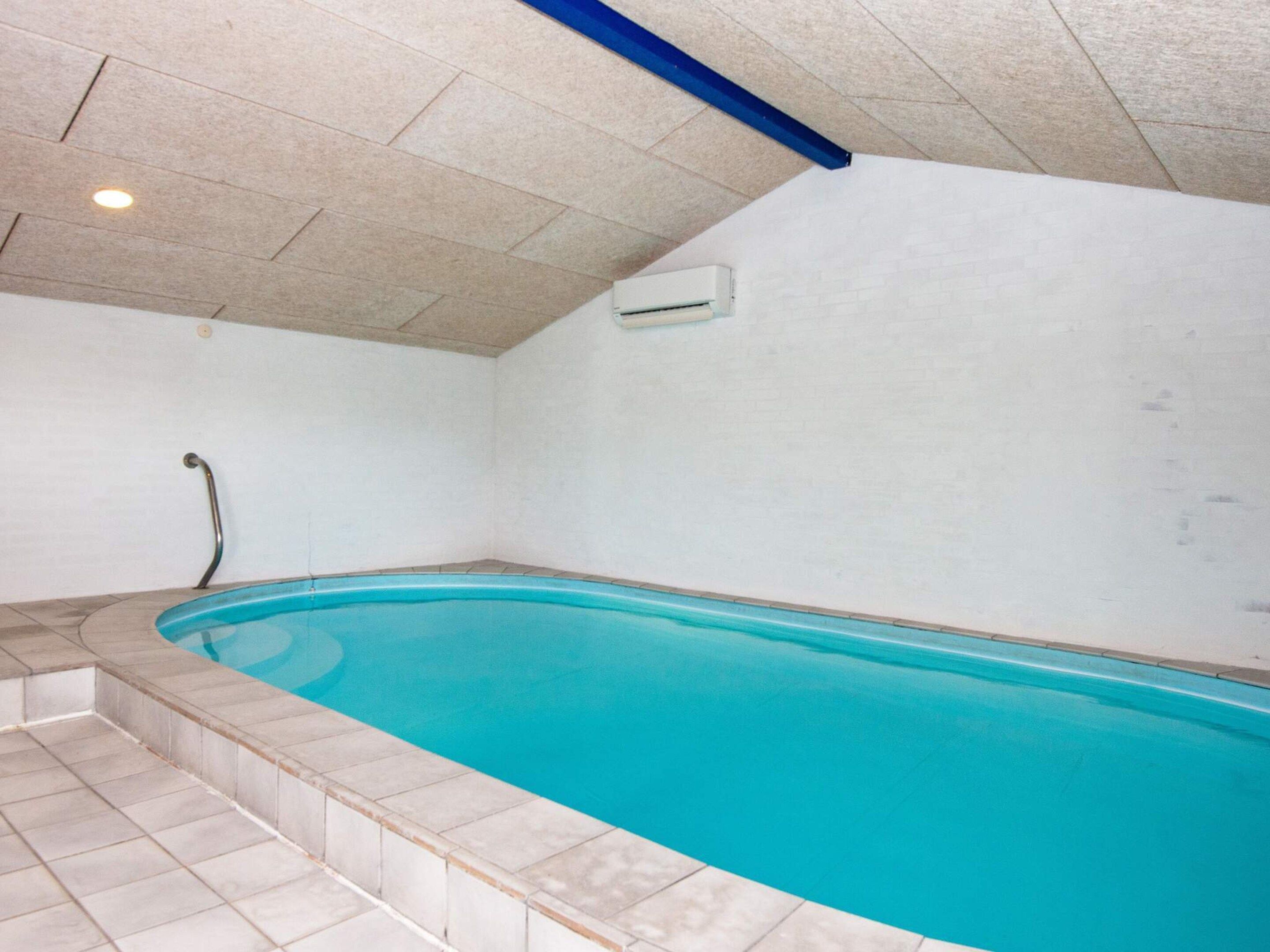 A swimming pool with a tiled deck and a handrail.