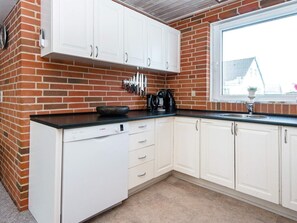 A kitchen with white cabinets, a Bosch dishwasher, and a window with a view of a house. - 8 Person Holiday Home in Harboore (Harboore)