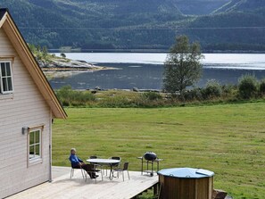 A house with a deck overlooking a lake, a barbecue setup, and a wooden shed. - Holiday Home in FÃ¸llenslev (Nærøysund)
