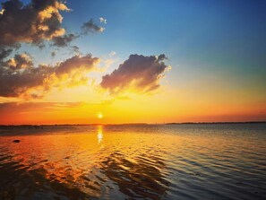 A sunset over a calm body of water with a bridge in the distance.