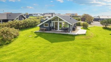 A modern house with a large lawn, a patio with outdoor furniture, and a garage.