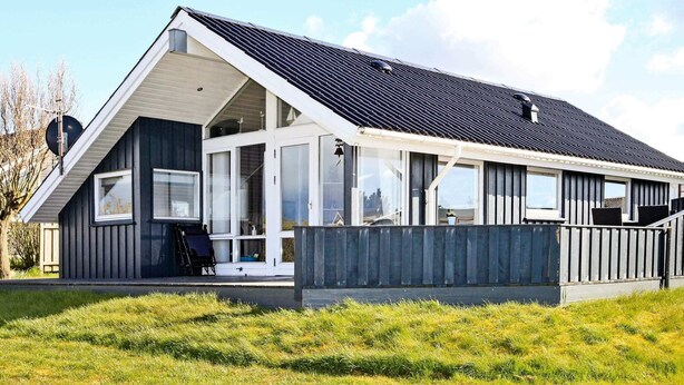 Ein modernes Haus mit geneigtem Dach, großen Fenstern und einer Veranda.