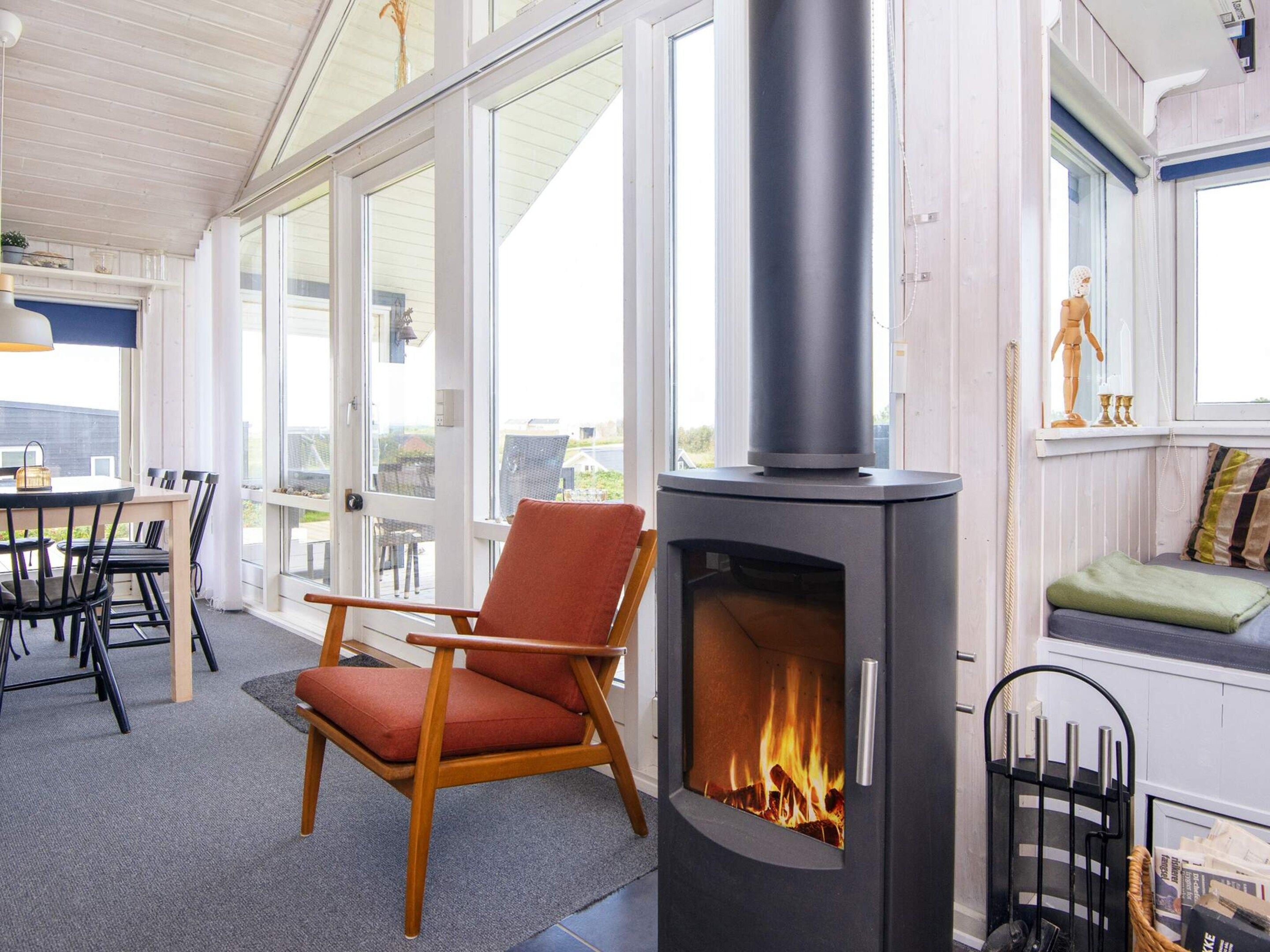 A room with a fireplace, a dining area, and a view through large windows.