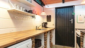 A compact kitchen with a wooden countertop, a coffee maker, and a black door. - 4 Person Holiday Home in Tranekaer (Tranekaer)