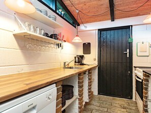 A compact kitchen with a wooden countertop, a coffee maker, and a black door. - 4 Person Holiday Home in Tranekaer (Tranekaer)