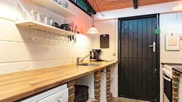 Una cocina compacta con encimera de madera, cafetera y una puerta negra.