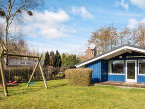 A residential property with a blue house, a swing set, and a well-maintained lawn. - Superb Holiday Home in Hemmet near Sea (Hemmet)