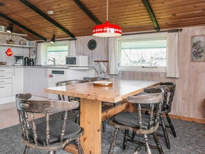 A kitchen with a wooden table, chairs, a clock, and a window with curtains. - Superb Holiday Home in Hemmet near Sea (Hemmet)